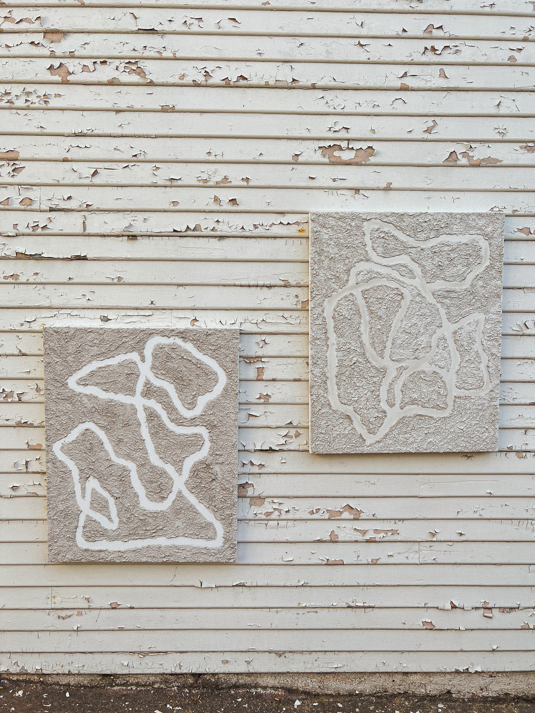 Textured painted artworks side by side on gritty distressed wall, showcasing modern primitive aesthetics of Parker Heath art