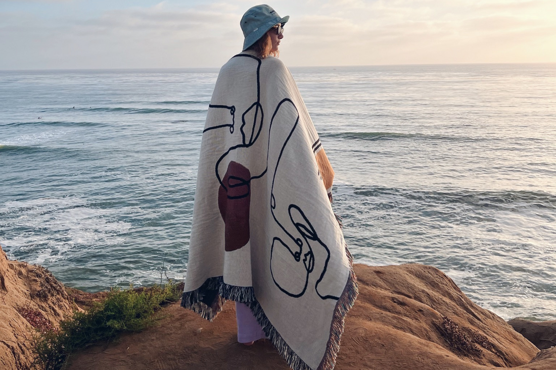 woman watching sunset edge of cliff wrapped in woven artwork throw blanket by PAR  KER made